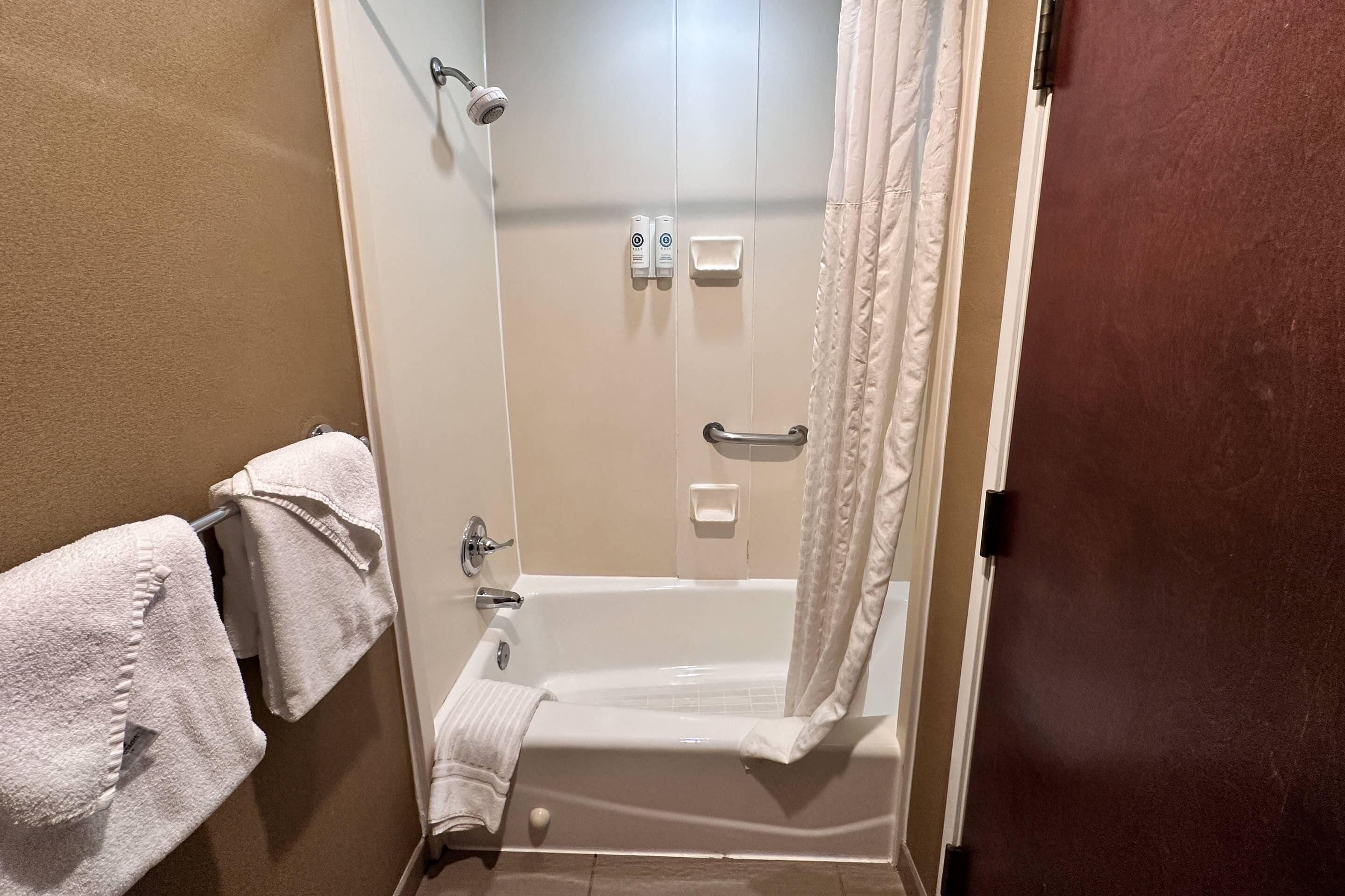 Un bagno con una vasca, una doccia, un portasciugamani e una porta.