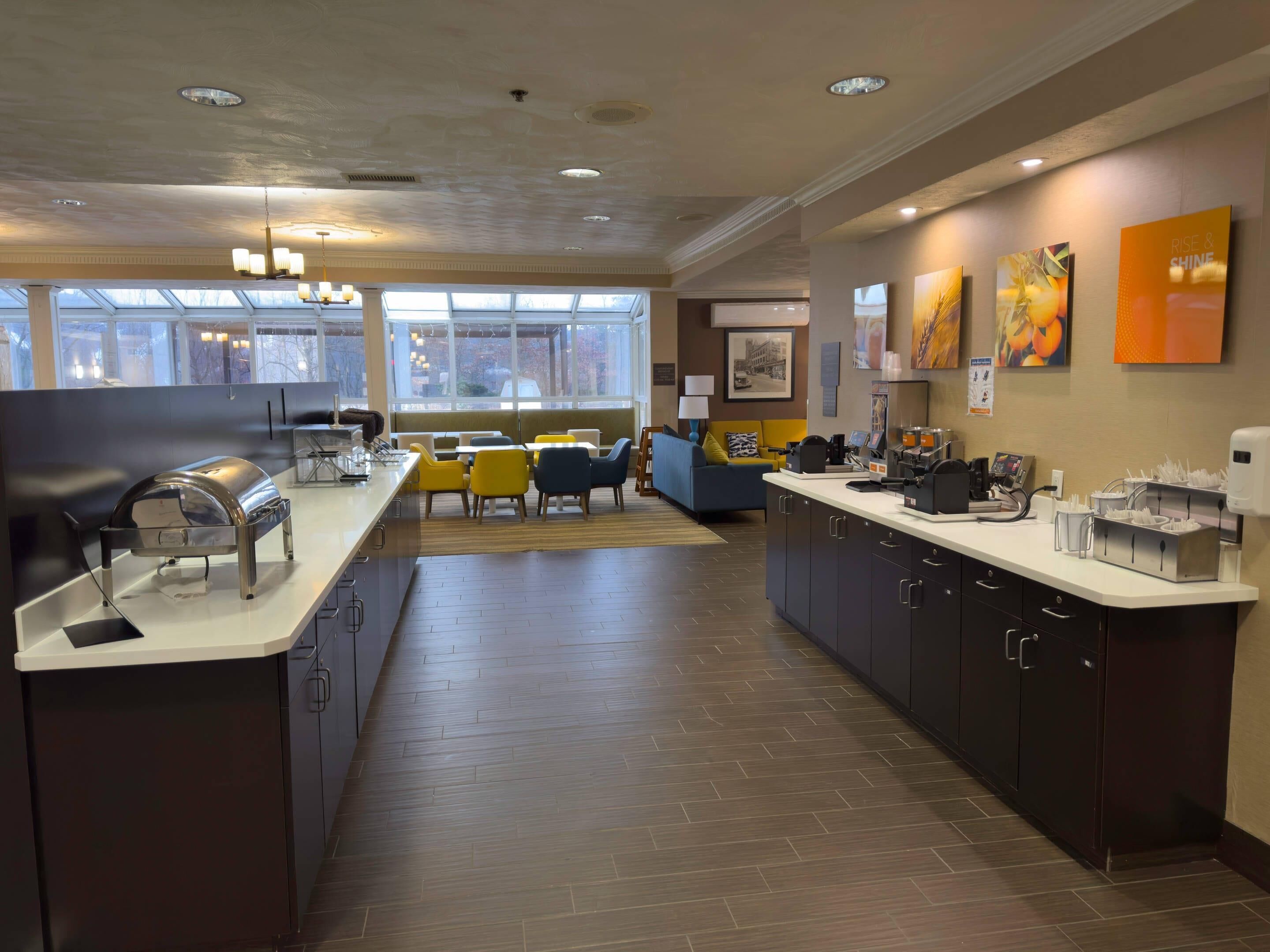 A modern hotel lobby with a reception desk, seating area, and artwork on the walls.