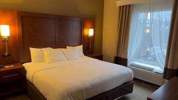 Une chambre d’hôtel avec un grand lit, deux lampes de chevet, une fenêtre avec des rideaux et un climatiseur fixé au mur.