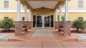 A building entrance with a covered walkway, brick pillars, and glass doors.