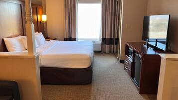 A hotel room with a bed, a desk, a television, and a window with curtains.