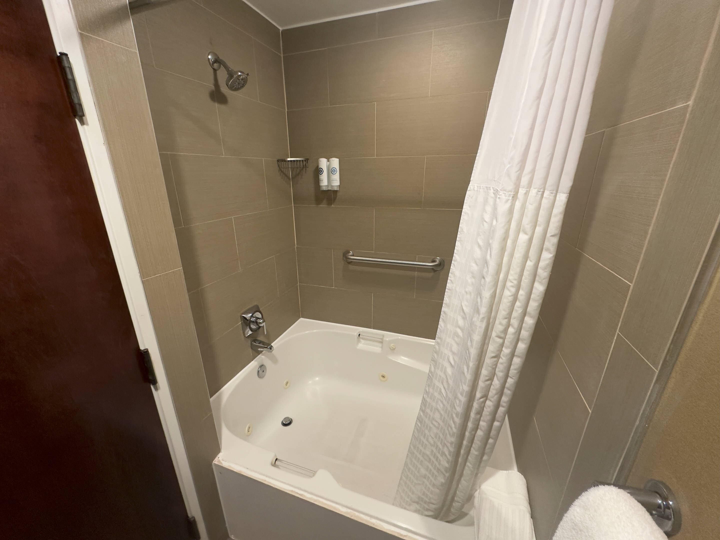 Een badkamer met een bad, douchekop, handdoekrek en toilet.