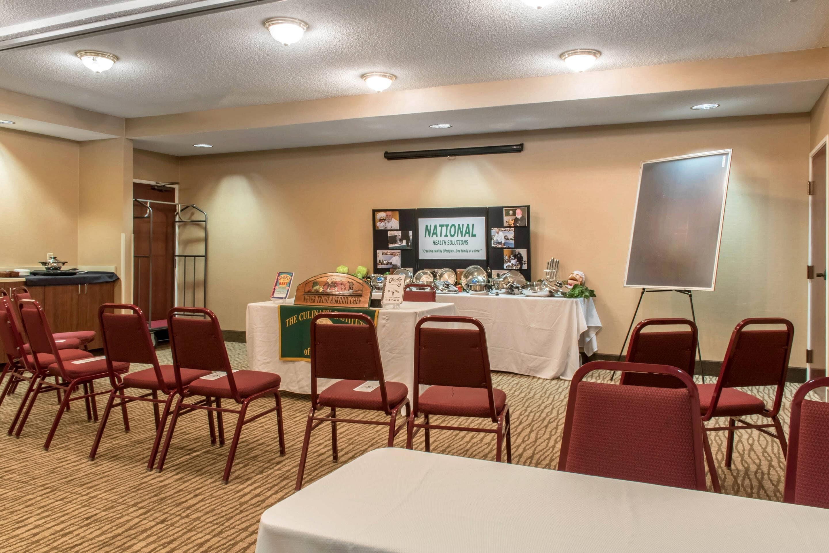 A conference room with a table, chairs, a podium, and a banner.