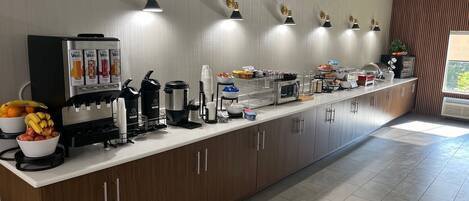 Eine moderne Küche mit einer langen Arbeitsplatte, ausgestattet mit einer Kaffeemaschine, einer Mikrowelle und verschiedenen Lebensmitteln.