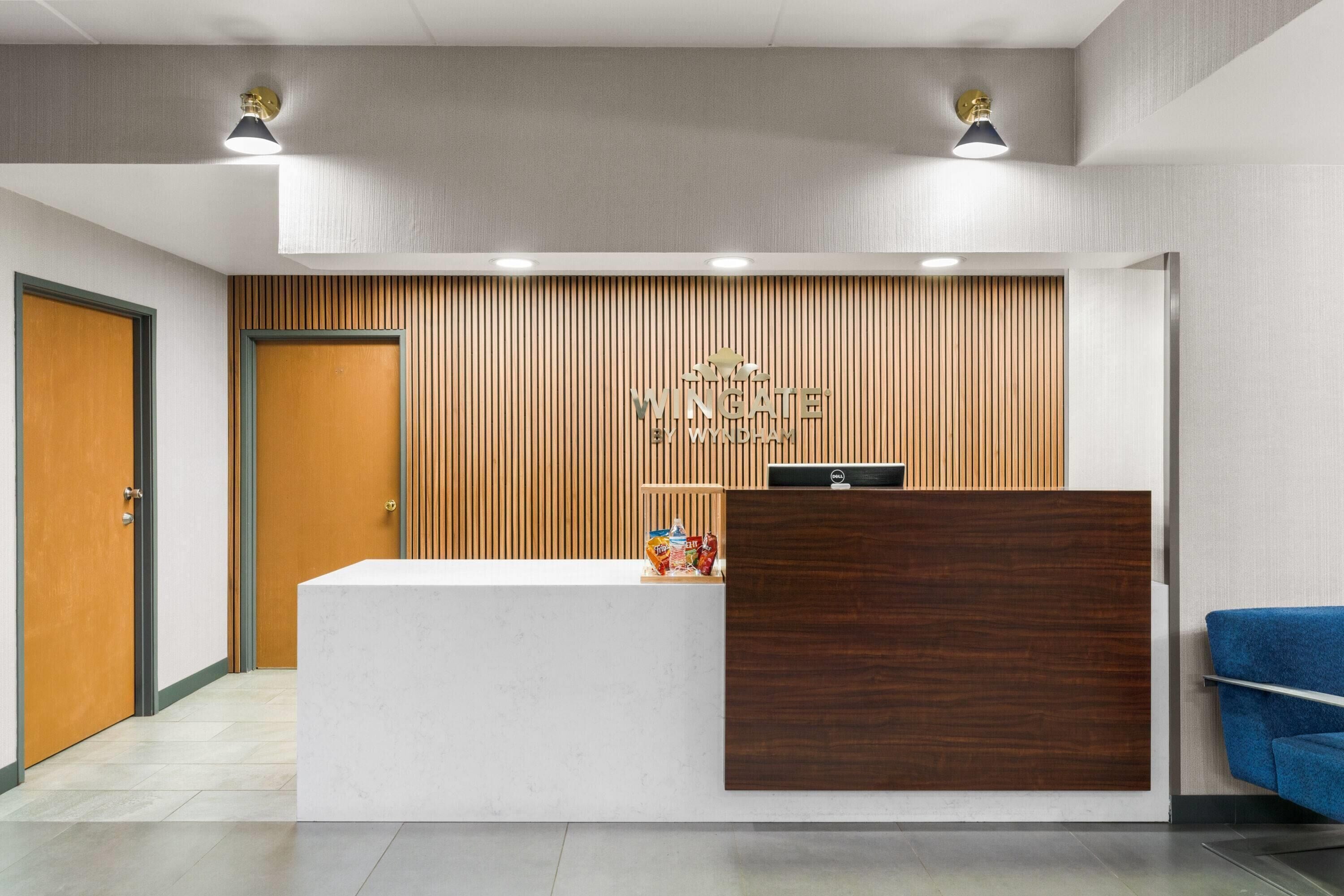 A reception area with a wooden panel wall, a reception desk, and a blue sofa.
