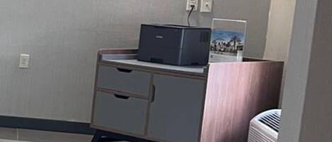 A small room with a desk, a printer, and a wall-mounted air conditioner.