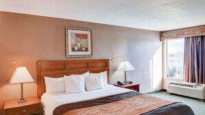Una habitación de hotel con una cama grande, dos mesitas de noche, una ventana con cortinas y un cuadro colgado en la pared.