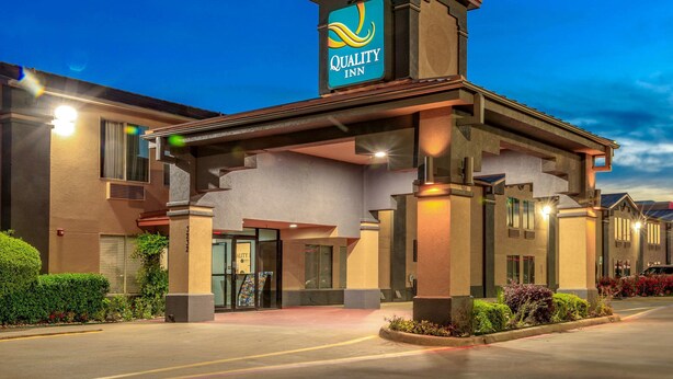 Un hotel Quality Inn con un letrero llamativo, una entrada cubierta y una fachada bien iluminada.