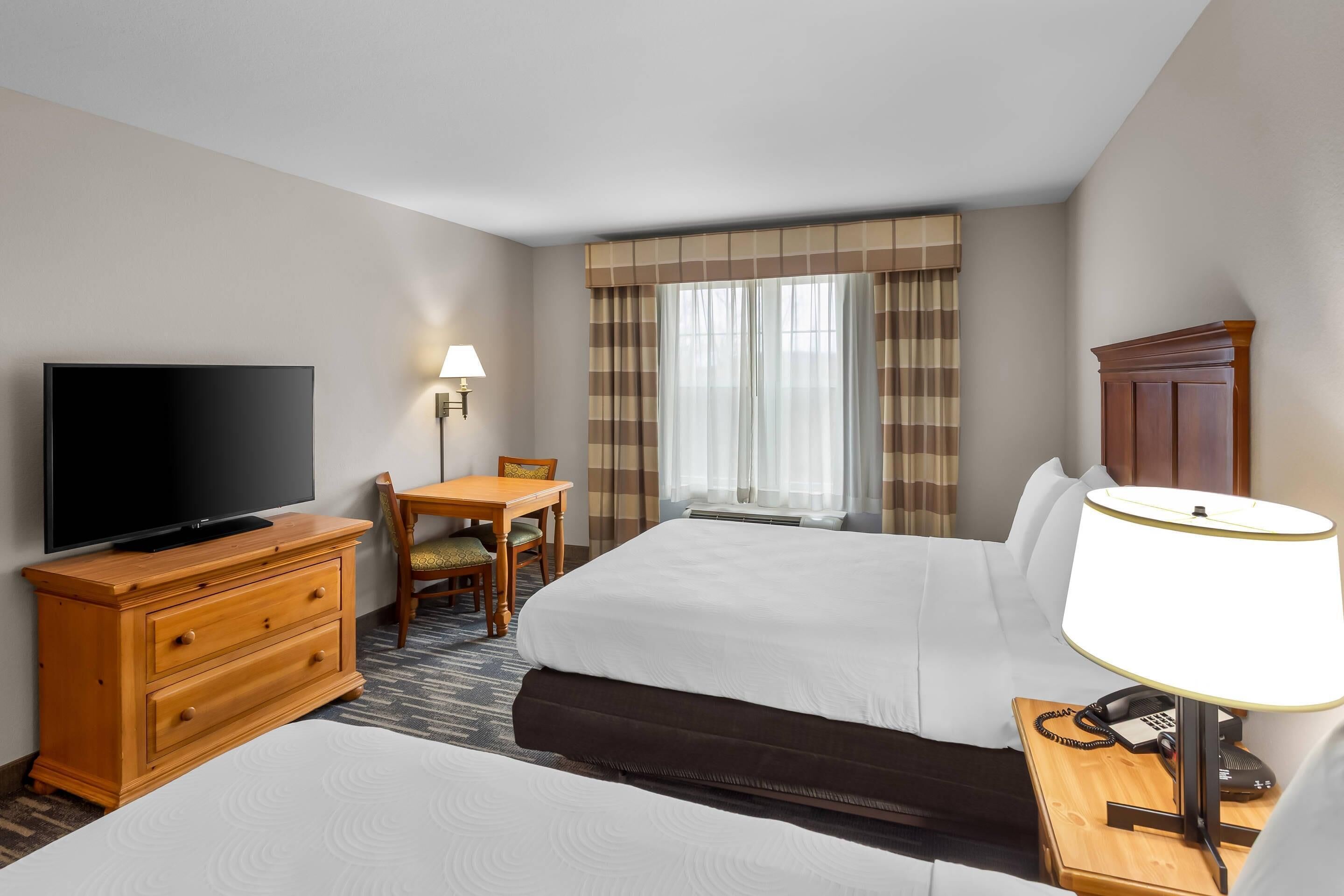 Camera d'albergo con un letto, una televisione, una scrivania, una sedia, una lampada e un armadio.