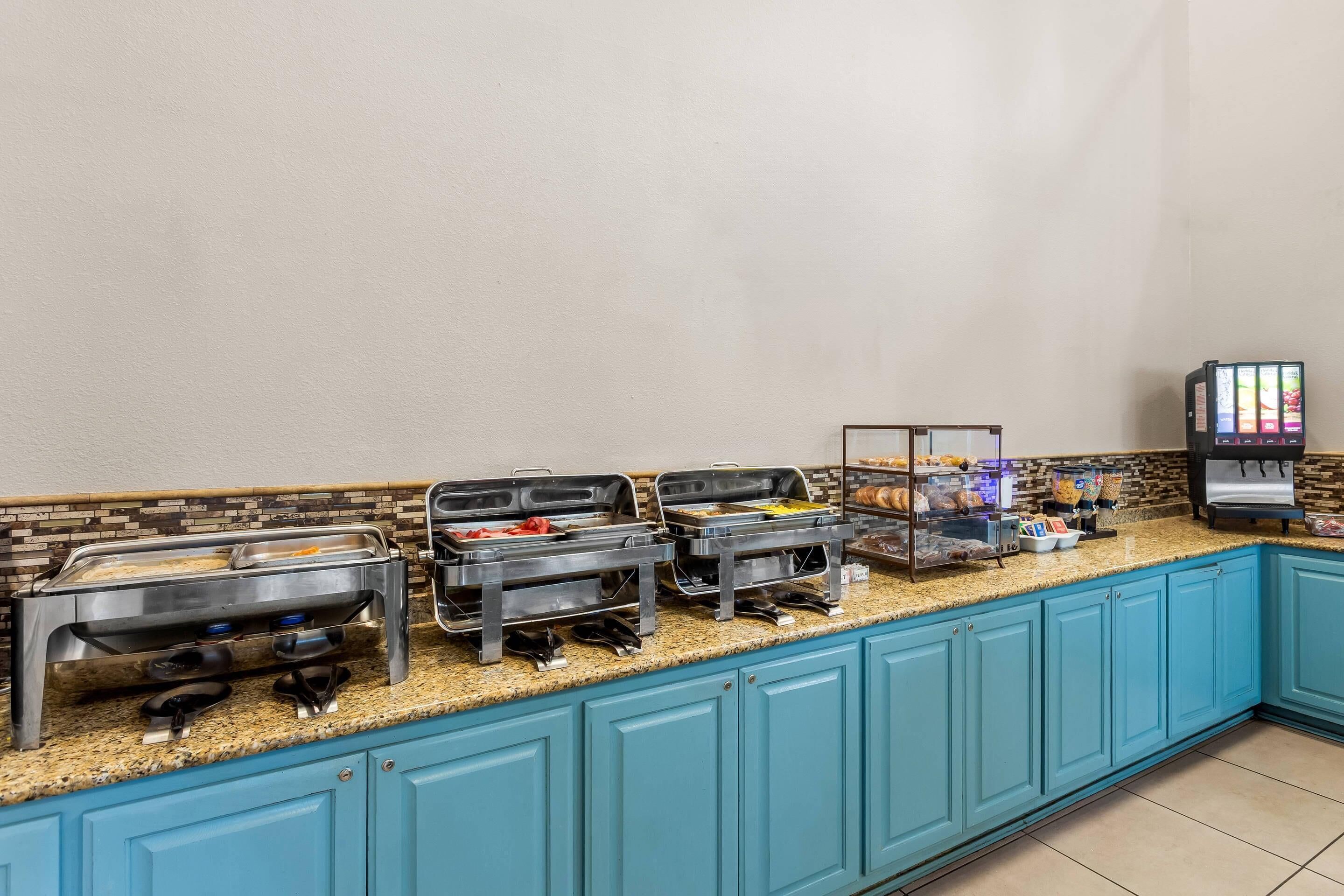 A buffet setup with multiple food stations, a coffee machine, and a beverage dispenser.