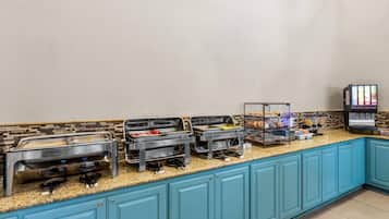 A buffet setup with multiple food stations, a coffee machine, and a beverage dispenser.