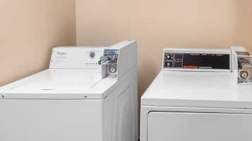 Two front-loading washers, Whirlpool and Speed Queen, in a laundry room with beige walls.