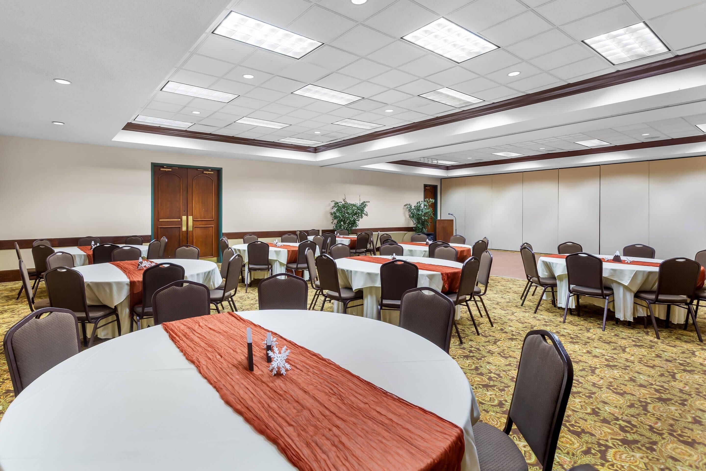 A conference room with round tables, chairs, and a carpeted floor.