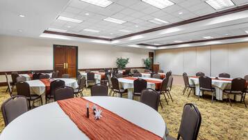 A conference room with round tables, chairs, and a carpeted floor.