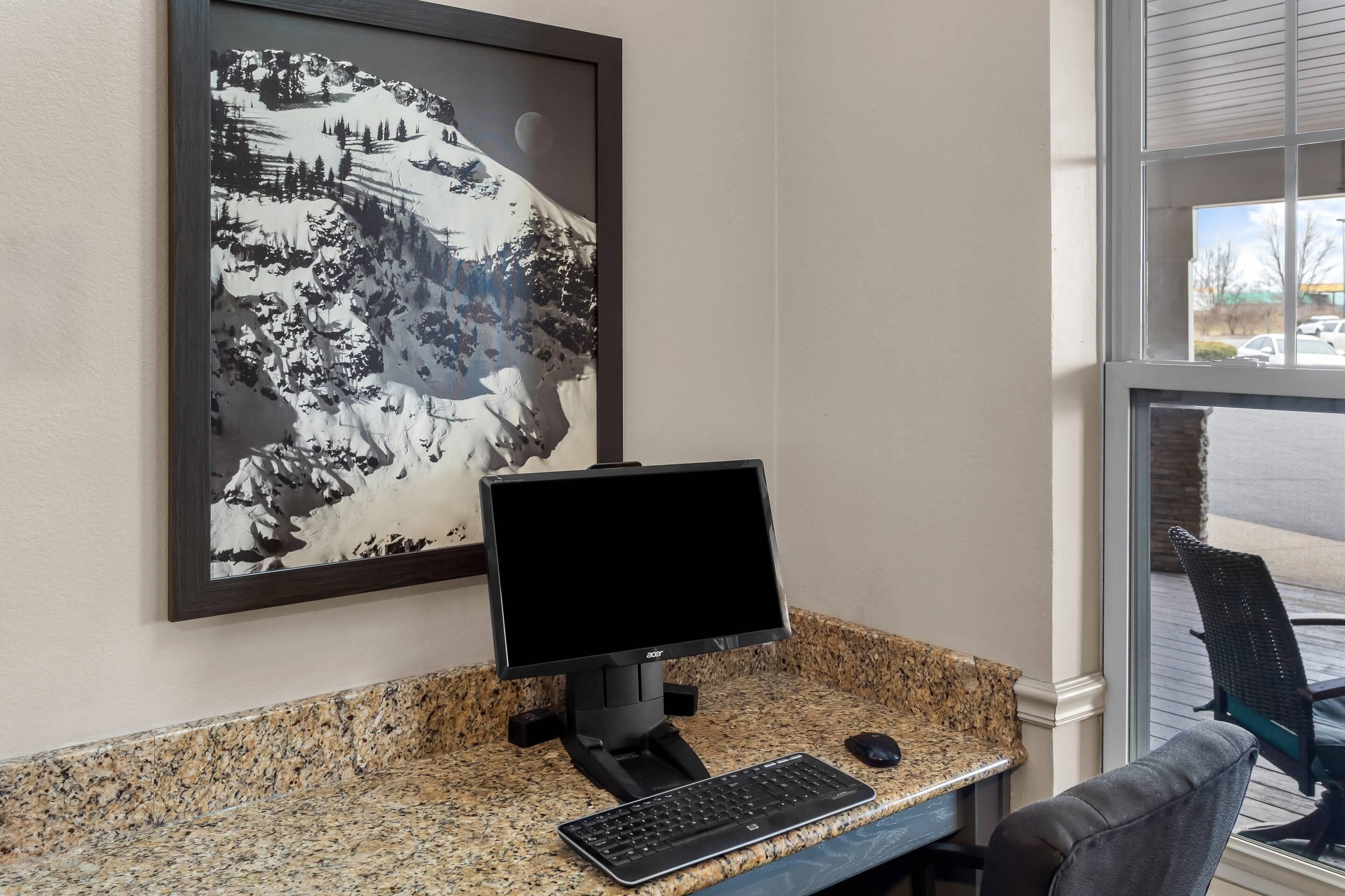 A computer desk with a monitor, keyboard, and mouse.