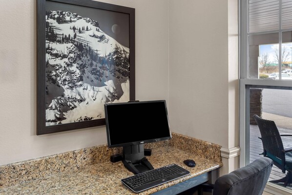 A computer desk with a monitor, keyboard, and mouse.