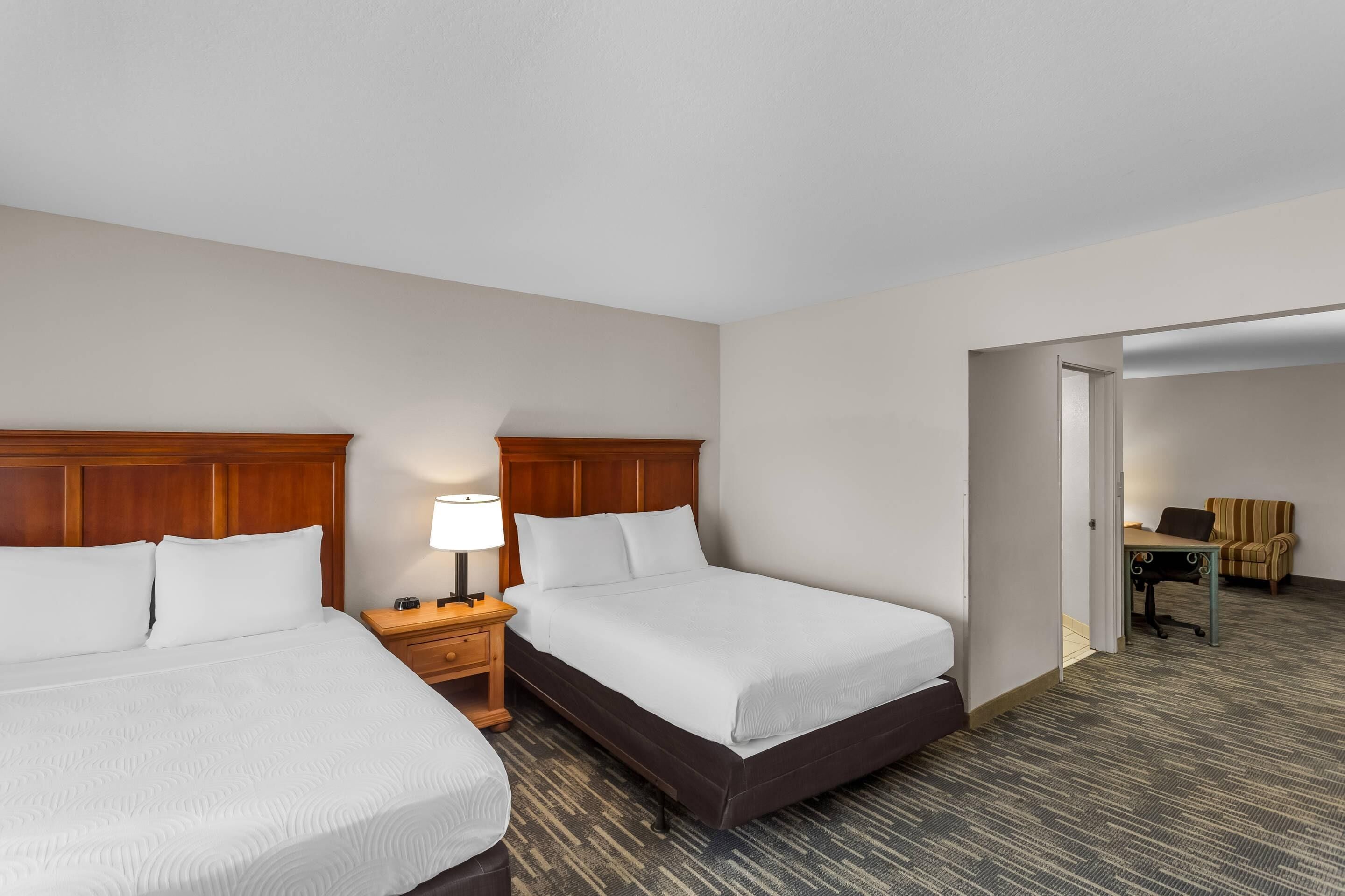 Ein Hotelzimmer mit zwei Betten, einem Schreibtisch und einem Stuhl.