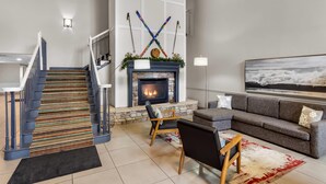 Un salon moderne avec une cheminée, un escalier et un grand tableau accroché au mur.