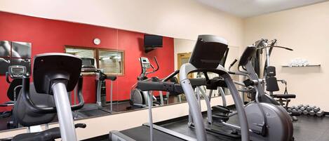 A gym with treadmills, a stationary bike, and dumbbells.