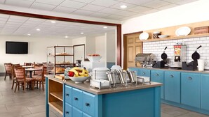 A modern kitchen with blue cabinets, a breakfast bar, and a dining area with wooden chairs. - Country Inn & Suites by Radisson, Kearney, NE (Kearney)
