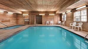 An indoor swimming pool with wooden walls and ceiling, surrounded by white plastic chairs. - Country Inn & Suites by Radisson, Kearney, NE (Kearney)