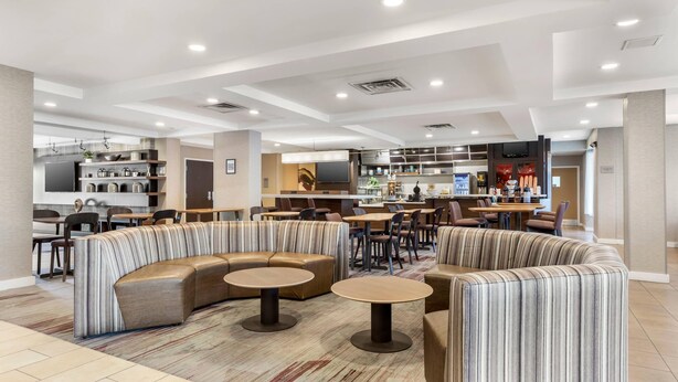 Un moderno vestíbulo de hotel con una zona de estar, un bar y una cocina al fondo.