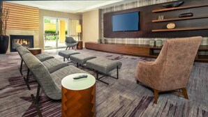 Una sala de estar moderna con chimenea, televisor de pantalla plana y una zona de estar con sofá y sillones.