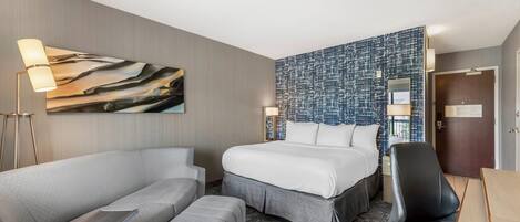 Una habitación de hotel con cama, sofá, escritorio y silla.