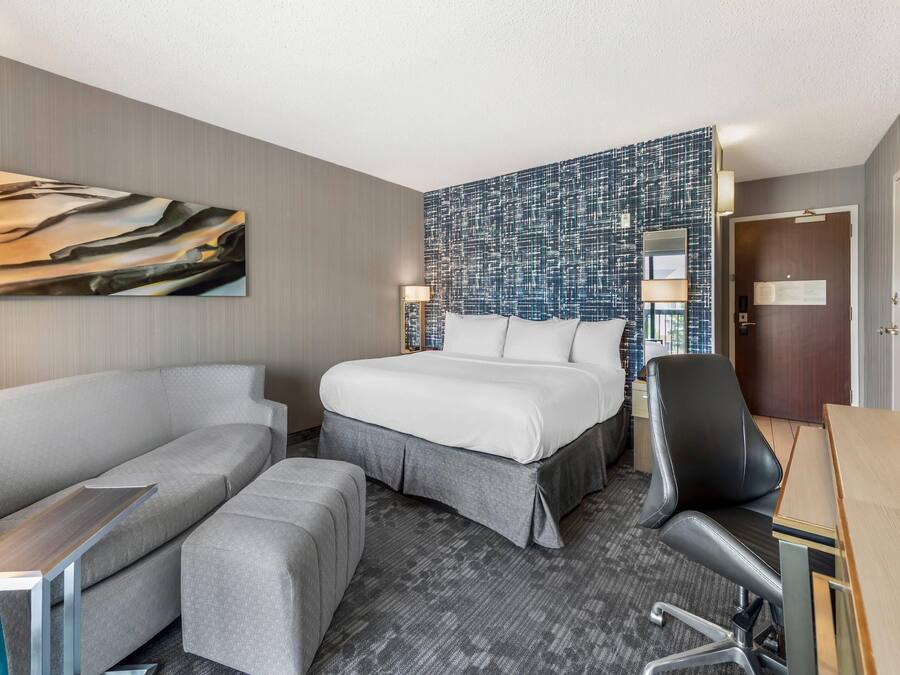 Una habitación de hotel con cama, sofá, escritorio y silla.