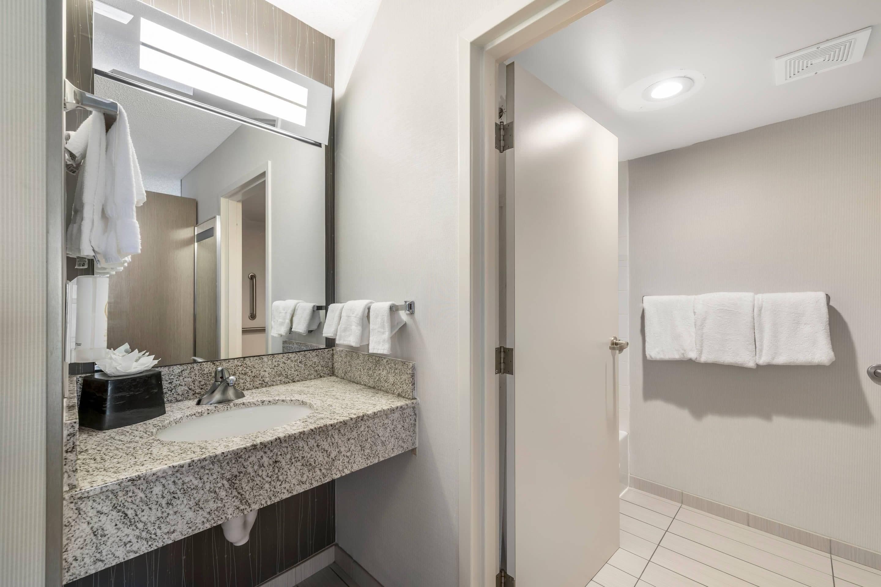 A bathroom with a granite countertop sink, a mirror, and a towel rack.
