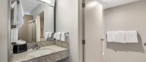 A bathroom with a granite countertop sink, a mirror, and a towel rack.