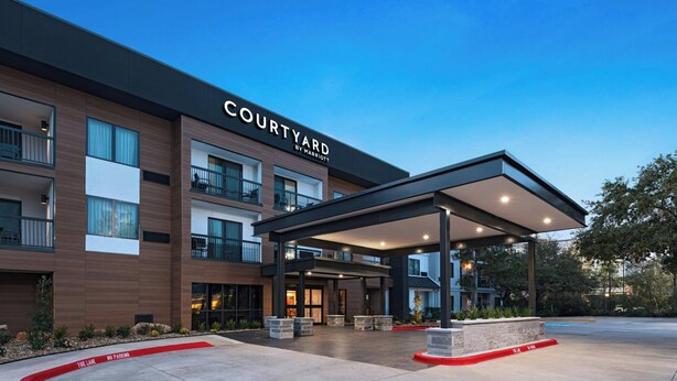 A Courtyard by Marriott hotel with a covered entrance, outdoor seating, and a fire lane. - Courtyard Houston The Woodlands (The Woodlands)