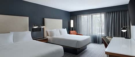 Een hotelkamer met twee bedden, een bureau en een stoel.