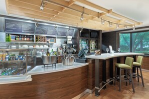 Un área de bar moderna con techo de madera, una pizarra de menú y una barra con taburetes.