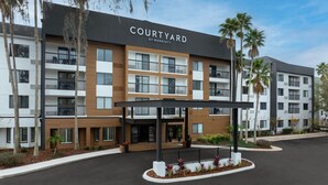 Un hotel Courtyard by Marriott de diseño moderno, con varios balcones y una zona de entrada cubierta.