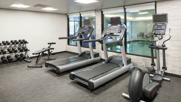 A gym with treadmills, dumbbells, and a stationary bike.