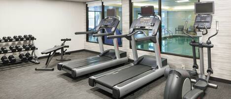 Une salle de sport équipée de tapis de course, d’haltères et d’un vélo d’appartement.