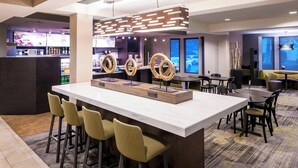 Un área de bar moderna con una barra alargada, taburetes y anillos decorativos.
