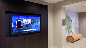 Un panel de menú digital en el vestíbulo de un hotel que muestra opciones de comida y bebida.