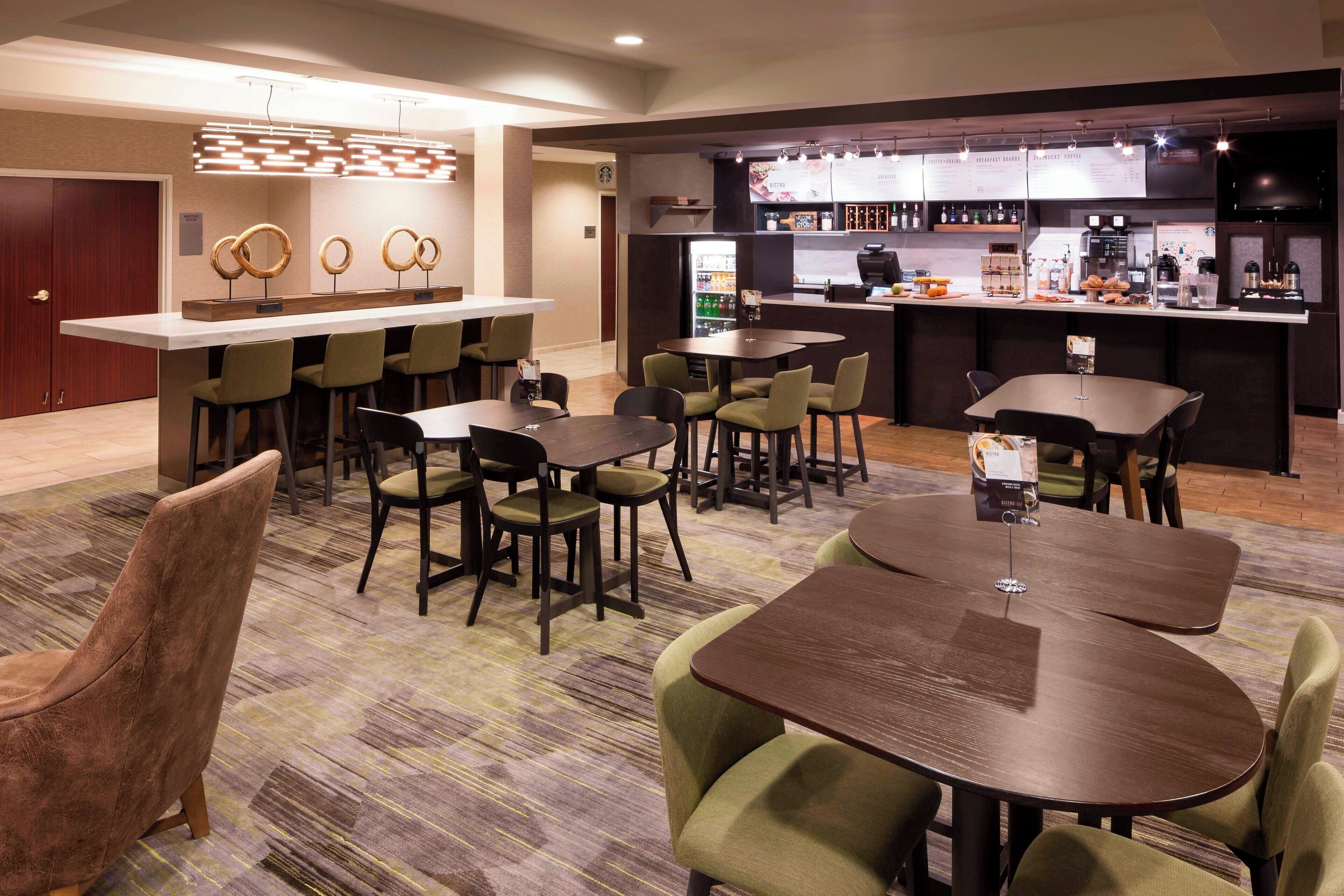 A hotel lobby with a bar area, seating arrangements, and a reception desk.