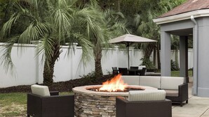 Un patio al aire libre con un hogar de piedra, muebles de mimbre y una zona de estar cubierta.