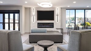 Ein modernes Wohnzimmer mit großem Flachbildfernseher, grauen Sofas, einem Couchtisch und einem Kamin.