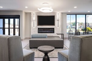 Una sala de estar moderna con un televisor de pantalla plana grande, sofás grises, una mesa de centro y una chimenea.