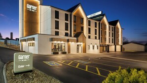 Ein Hotel mit einem gut sichtbaren 'Garnier by IHG'-Schild, einem Parkplatz inklusive Stellplätze für Menschen mit Behinderung und einem gut beleuchteten Eingang.