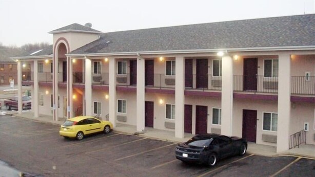 A motel with multiple rooms, a parking lot, and a yellow car parked in front. - Townhouse Inn & Suites (Omaha)
