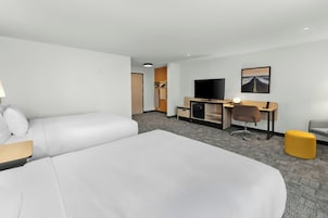 A hotel room with a bed, a desk, a television, and a chair.
