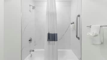A modern bathroom with a glass-enclosed shower, a white bathtub, and a towel rack with towels.