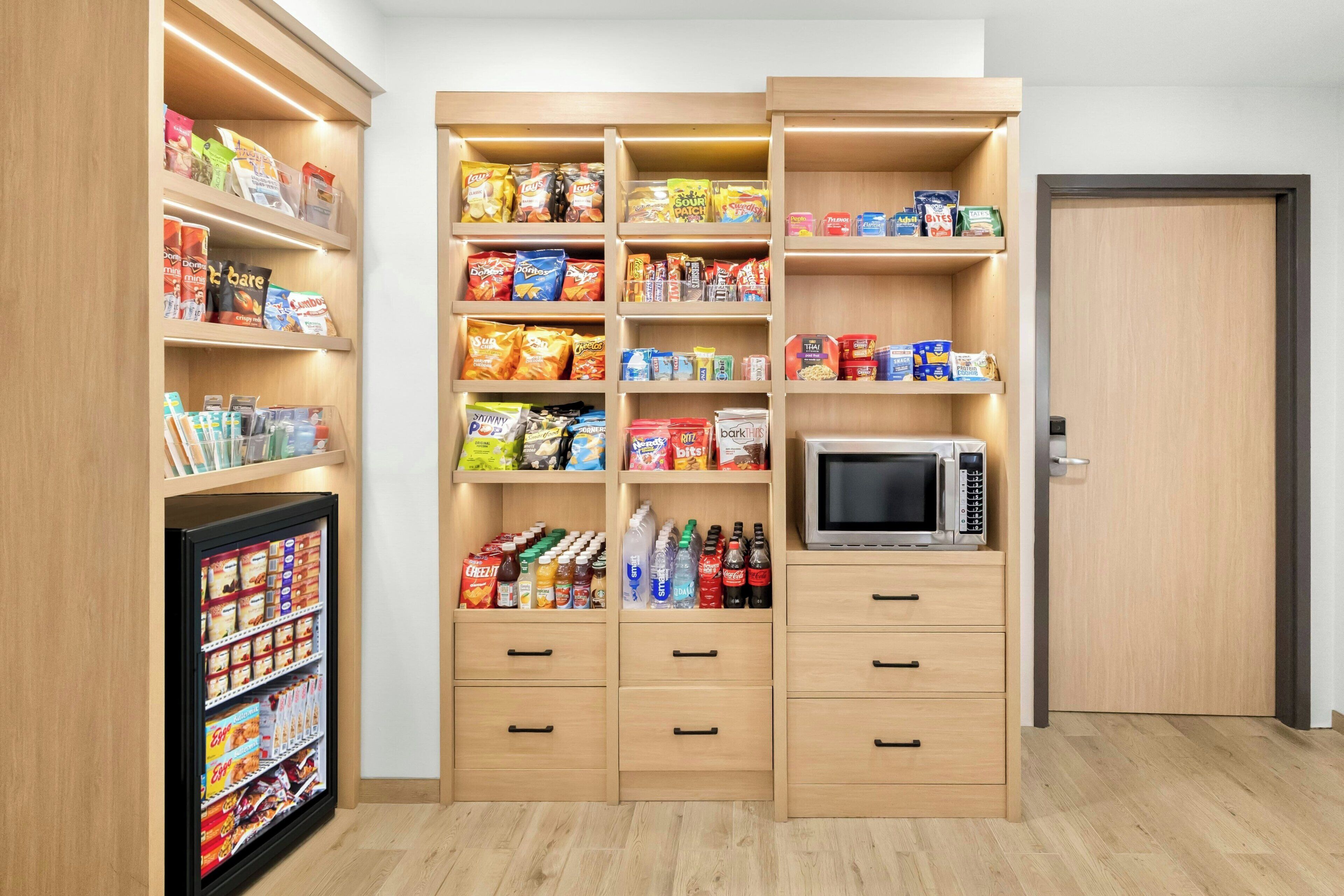 A kitchenette with a microwave, storage cabinets, and a refrigerator.