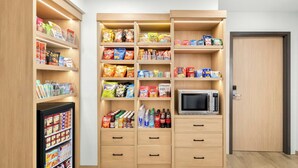 A kitchenette with a microwave, storage cabinets, and a refrigerator.