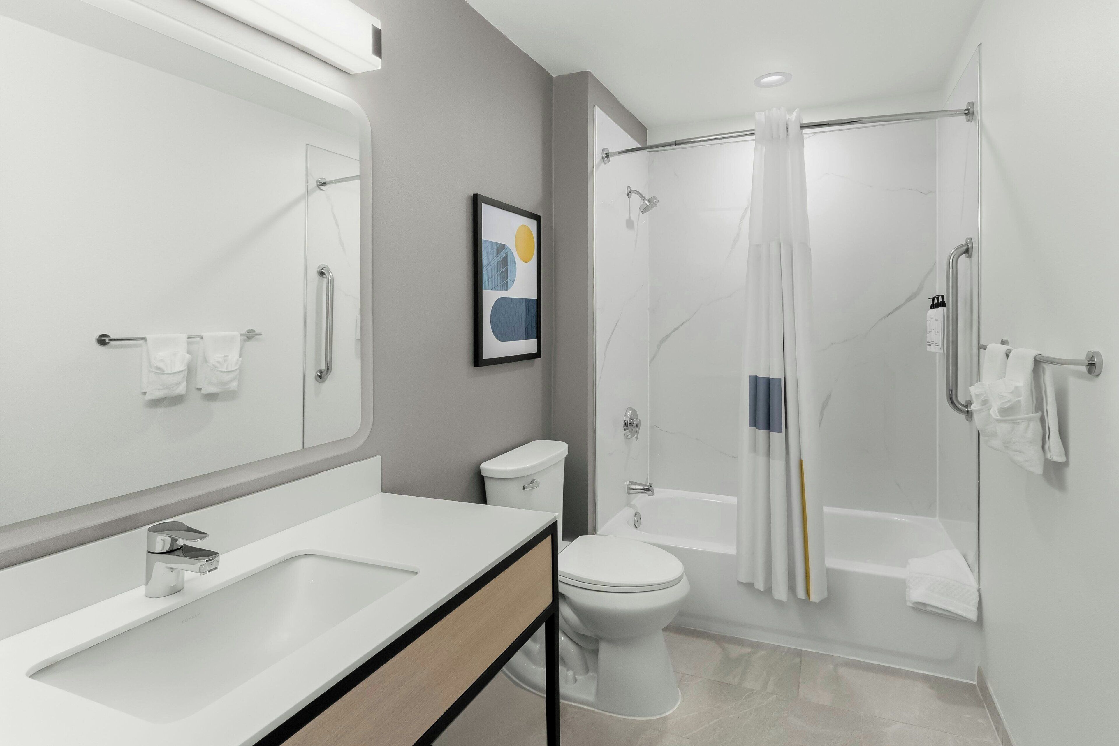 Een moderne badkamer met een grote spiegel, toilet, douche met glazen deur en een wastafel met houten kastje.